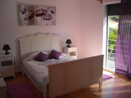 um quarto com uma cama com almofadas roxas e uma janela em Sweet Dreams AL em Ponta Delgada