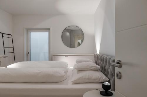 a white bedroom with two beds and a mirror at Pure Tinnum in Sylt