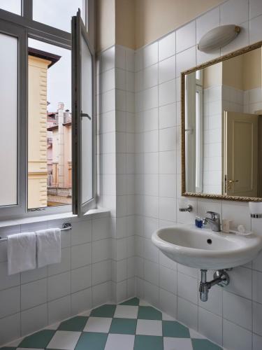 a bathroom with a sink and a mirror at Hotel Continental in Opatija