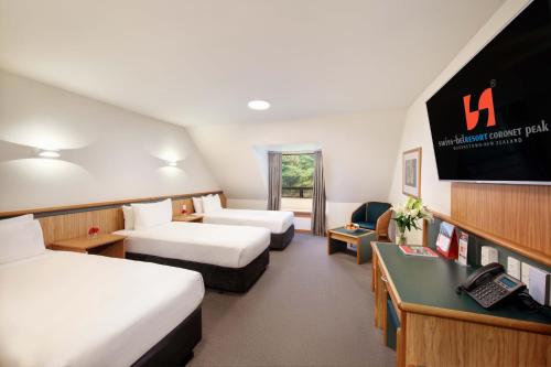 a hotel room with two beds and a television at Swiss-Belresort Coronet Peak in Queenstown