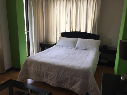 a bedroom with a bed with white sheets and a window at Hotel Oicatá in Duitama