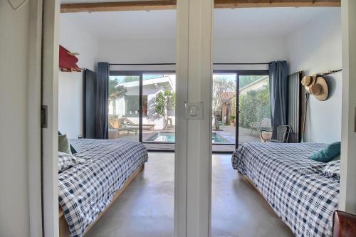two beds in a room with sliding glass doors at Maison d'architecte 4 chambres avec piscine in Anglet
