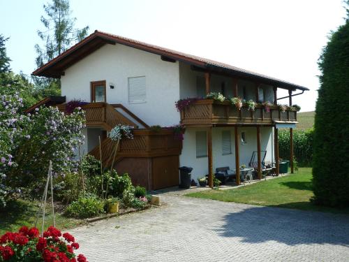a house with a balcony with flowers on it at Pension Sochor in Aidenbach