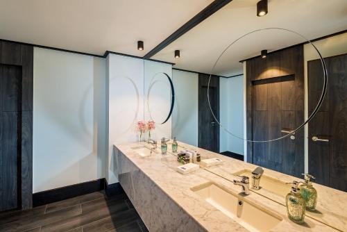 a bathroom with a sink and a large mirror at H10 Puerta de Alcalá 4 Sup in Madrid