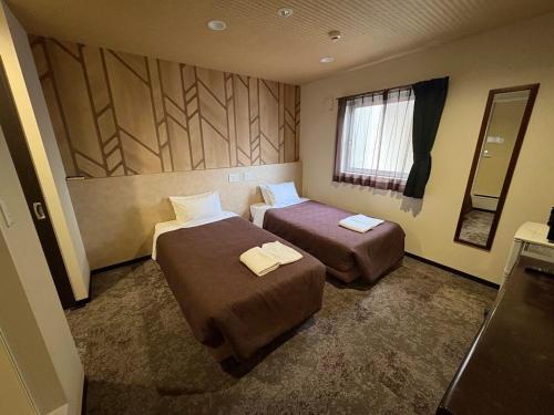 a hotel room with two beds and a window at HOTEL LiVEMAX Himeji Ekimae in Himeji