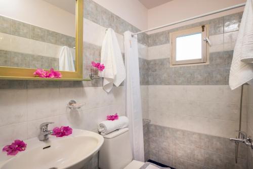 Un baño con lavabo, inodoro y espejo. en Orionas Village, en Kato Daratso