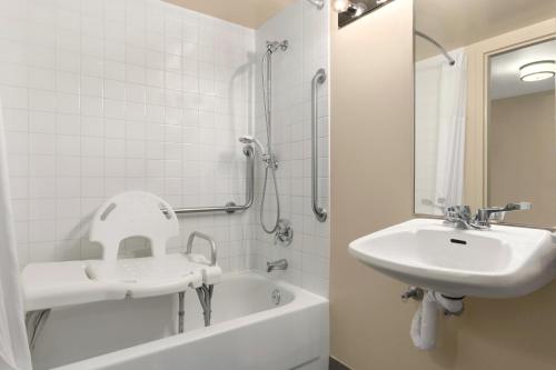 a white bathroom with a sink and a bath tub at Days Inn by Wyndham Stephenville in Stephenville