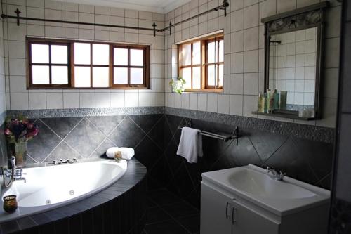 a bathroom with a tub and a sink at Greenleaf Guest Lodge in Bloemfontein