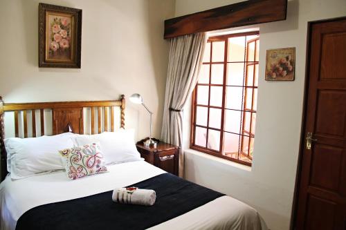 Bloemfontein的住宿－Greenleaf Guest Lodge，一间卧室设有一张大床和窗户