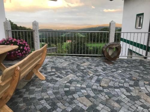 a patio with a bench and a table and flowers at Woidzeit by Sigl in Kollnburg