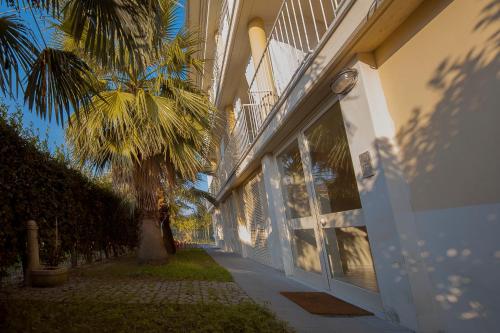 a building with a palm tree next to a sidewalk at ALBACHIARA INN Residence Apartments in Ameglia