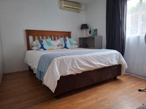 a bedroom with a large bed with blue and white pillows at Melrose Garden Cottages - Hibiscus Cottage in Durban