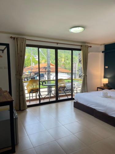 a bedroom with a bed and a balcony with a table and chairs at Lemon Inn in Ko Lanta