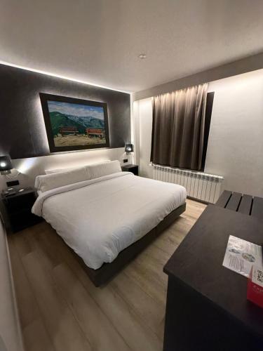 a bedroom with a large white bed and a desk at Hotel Guineu in Pas de la Casa