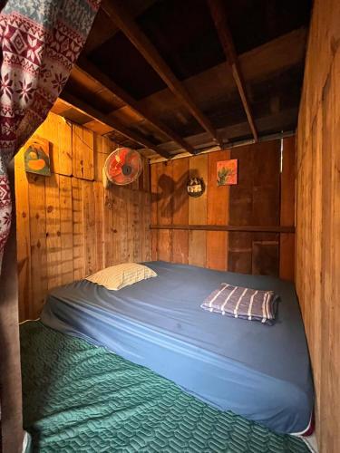 a bed in a wooden room with a blue blanket at Cactos Chill & Homestay in Ho Chi Minh City