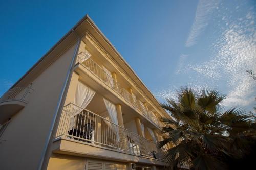 un edificio con balcón y una palmera en ALBACHIARA INN Residence Apartments, en Ameglia