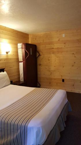 a bedroom with a bed in a room with wooden walls at Emerald Forest Cabins in Trinidad
