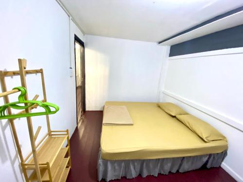 a small bedroom with a yellow bed and a ladder at J&T House And Friends in Ban Khlong Nam Ron