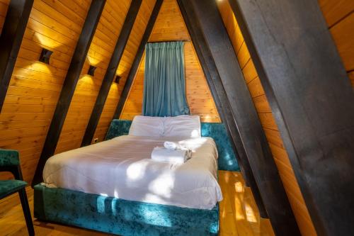 a bedroom with a bed in a room with wooden walls at Golden Cabins Gjinar by PikHost in Elbasan
