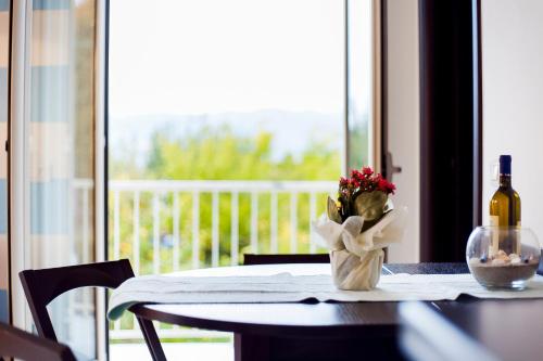 a table with a bottle of wine and a vase of flowers at ALBACHIARA INN Residence Apartments in Ameglia