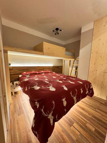 a bedroom with a bed with a red comforter at Lilli apartment in Aprica