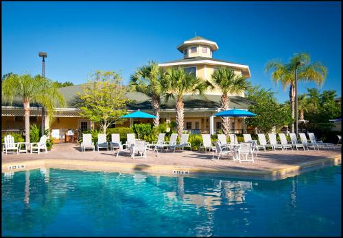 un complejo con piscina, sillas y un edificio en Caribe Cove Resort en Kissimmee
