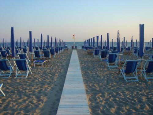 a row of chairs and umbrellas on a beach at ALBACHIARA INN Residence Apartments in Ameglia