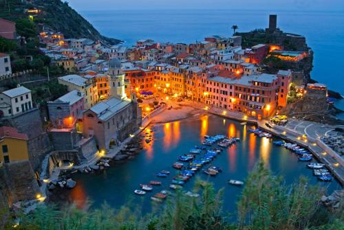 a city at night with boats in a harbor at ALBACHIARA INN Residence Apartments in Ameglia