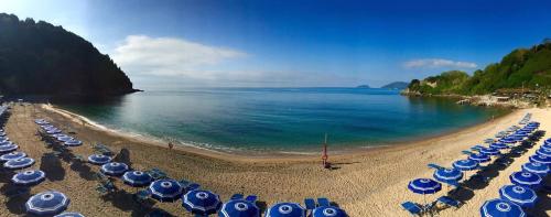 a beach with blue and white umbrellas and the ocean at ALBACHIARA INN Residence Apartments in Ameglia