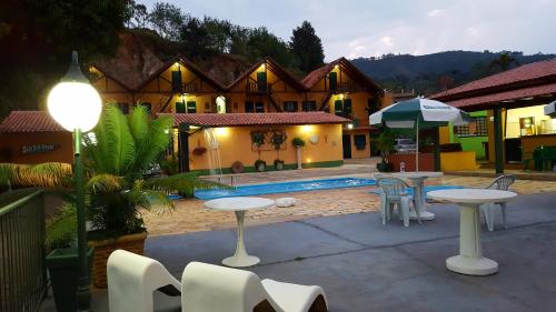 a patio with tables and an umbrella in front of a house at Pousada Villa Três in Serra Negra