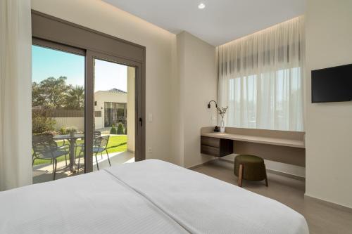 a bedroom with a bed and a desk and a balcony at Palm View Suites in Kourouta