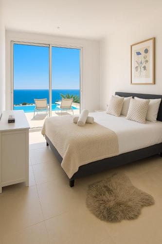 a bedroom with a bed and a view of the ocean at Lirios 182 Cumbre del Sol in Benitachell