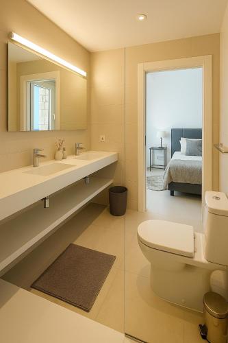 a bathroom with a toilet and a sink with a mirror at Lirios 182 Cumbre del Sol in Benitachell