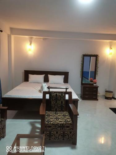 a bedroom with a bed with a mirror and a chair at Wadula Resort in Nochchiyagama