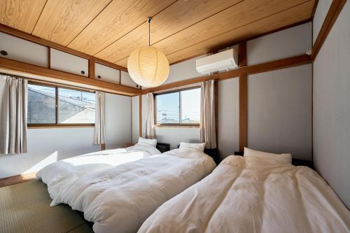 two beds in a room with wooden ceilings and windows at SAUNARF Aoshima in Miyazaki
