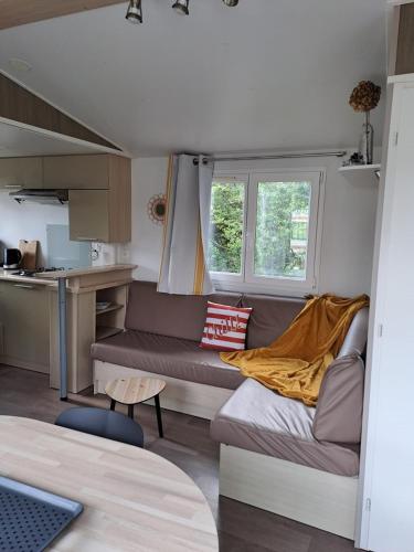 a living room with a couch and a kitchen at Camping le Kergorz in Plomodiern