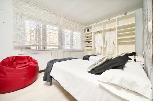 a bedroom with two beds and a red ottoman at Los Respigos Laredo in Laredo