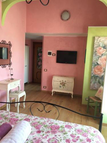 a bedroom with a pink wall with a tv at Villa Gaia - Luxury Villa, pool & wellness rooms in Bordighera