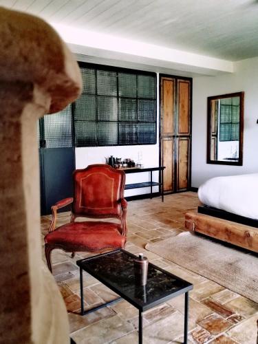 a bedroom with a bed and a chair and a coffee table at Auberge de la Roche in Valdeblore