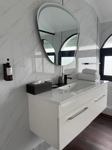 a white bathroom with a sink and a mirror at Résidence Hôtelière Océane in Libreville