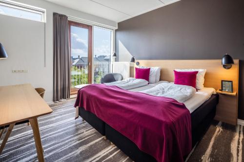 a bedroom with a large bed with a purple blanket at Hotel Kolding in Kolding