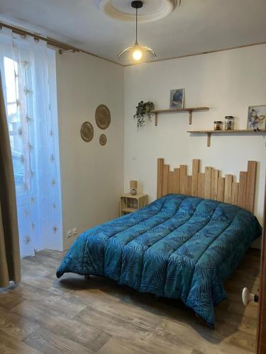 a bedroom with a large bed with a blue comforter at AUX ABORDS DU PoT BOUILLANT in Cromac