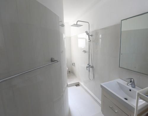a white bathroom with a shower and a sink at Dehiwala Holiday Villa in Dehiwala