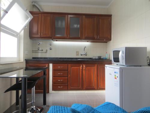 a kitchen with wooden cabinets and a white microwave at Apartamento Segundo Canto in Ponta Delgada
