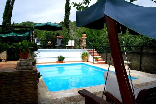 a swimming pool with an umbrella in a yard at Cortijo La Algallumbilla in Carcabuey