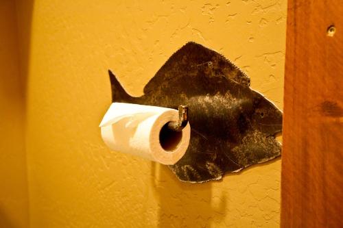 a toilet paper holder with a shark head on a wall at Baycrest Lodge in Homer