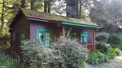 a small red shed with green windows in a garden at Emerald Forest Cabins in Trinidad