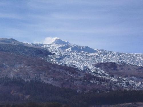 a snow covered mountain in the distance with a city at Il Calice dell'Etna in Passopisciaro