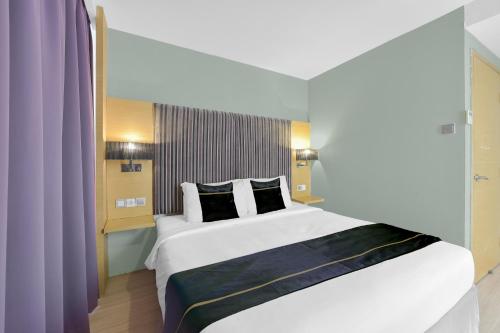 a bedroom with a large white bed with black pillows at Sunday Hotel Subang in Subang Jaya