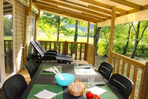 a screened porch with a table and chairs at ZEcamping 3 étoiles avec piscine chauffée en pleine nature in Belmont-sur-Rance